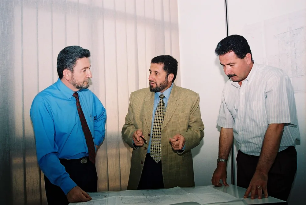 Three ALSUWEIDI colleagues discussing drawings in the early office